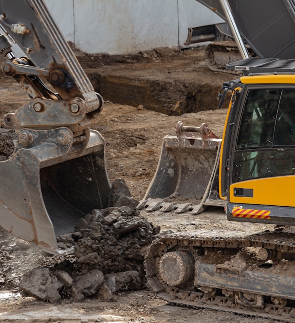 yellow and black excavator on brown soil