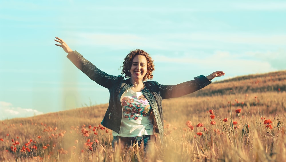 woman in black and white floral long sleeve shirt standing on brown grass field during daytime