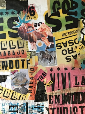 A vibrant and eclectic collage composed of various torn and layered posters and clippings. The collage includes images of a horse, a person holding a llama with blue glasses, and an open book. There are numerous texts and advertisements featuring different fonts, colors, and sizes, creating a chaotic and dynamic visual. The background consists of mixed colors like yellow, green, pink, and black, with fragments of paper and bold letters scattered throughout.