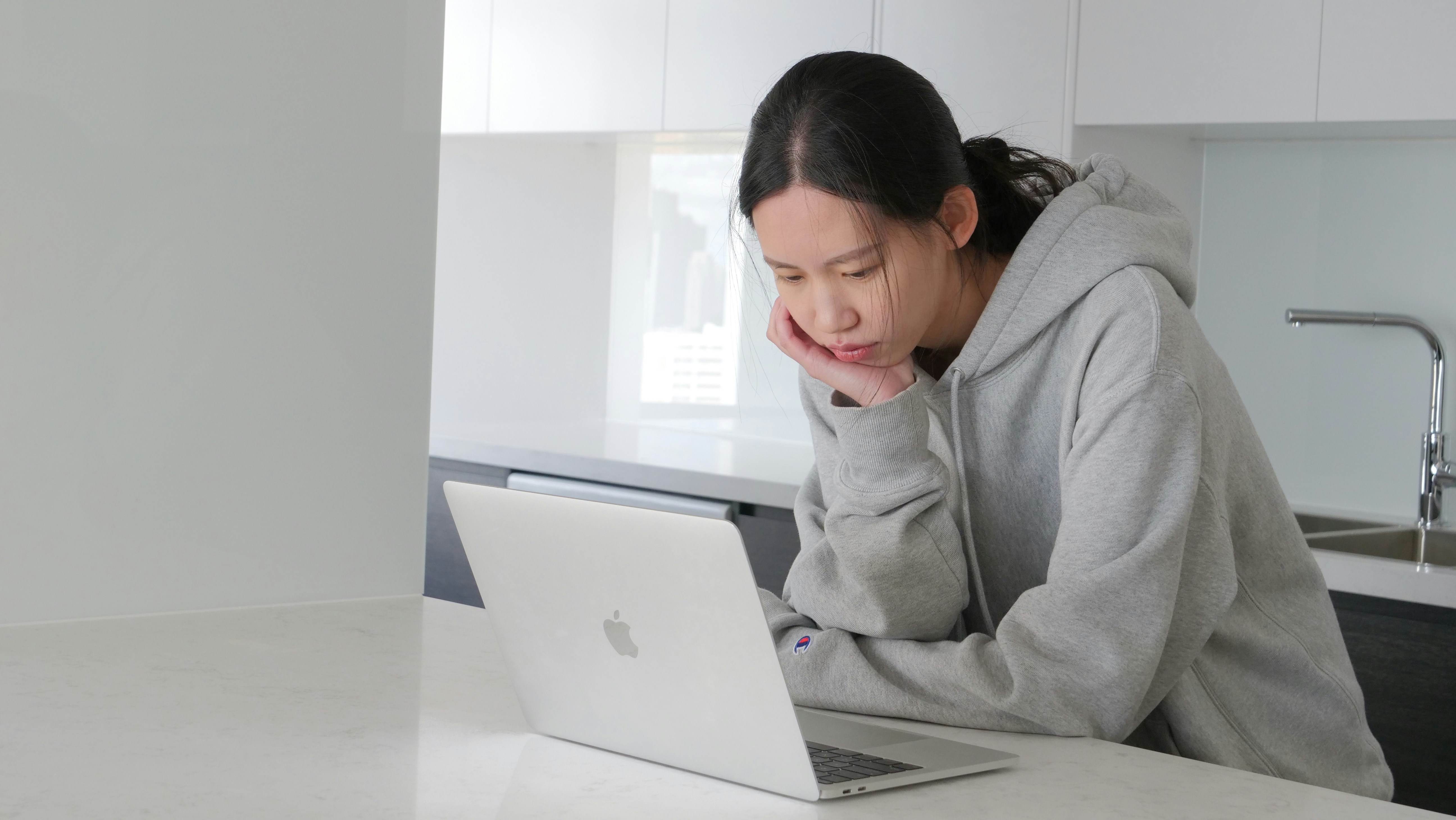 man in gray hoodie sitting beside white table