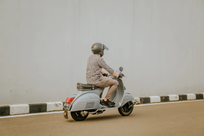 man in brown and white checkered dress shirt riding on gray motor scooter