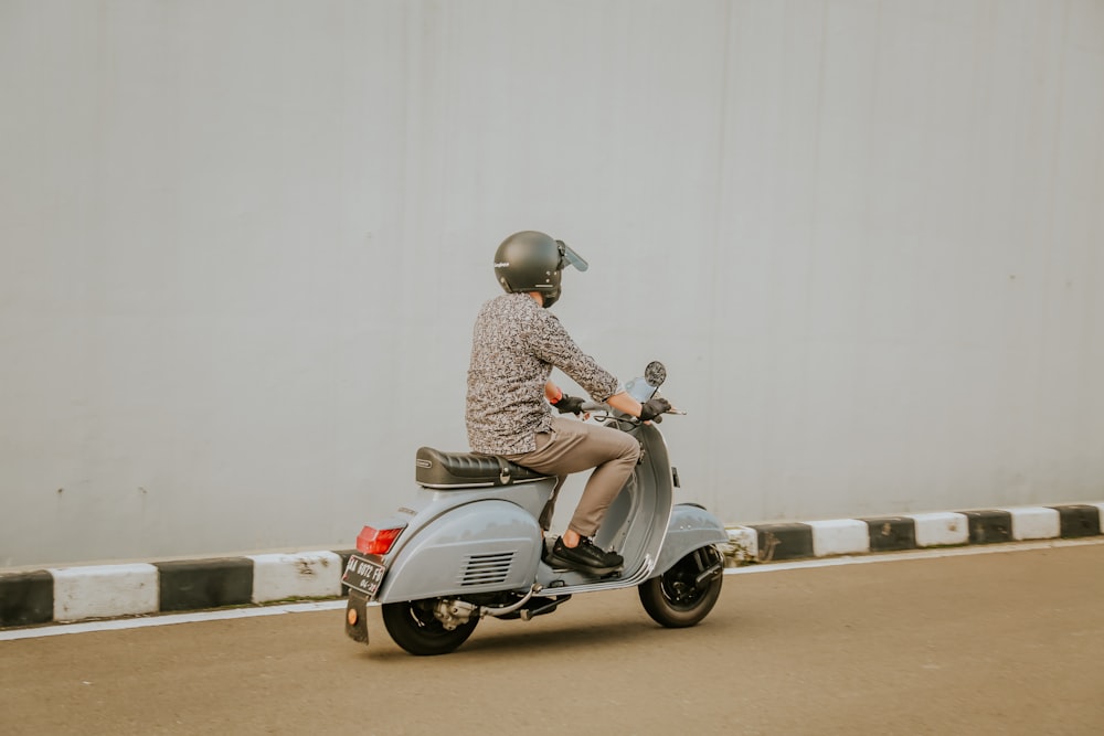 Hombre en camisa de vestir a cuadros marrón y blanco montando en scooter gris