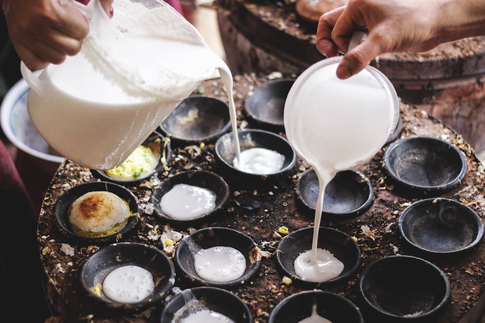 person pouring white liquid on white ceramic cup