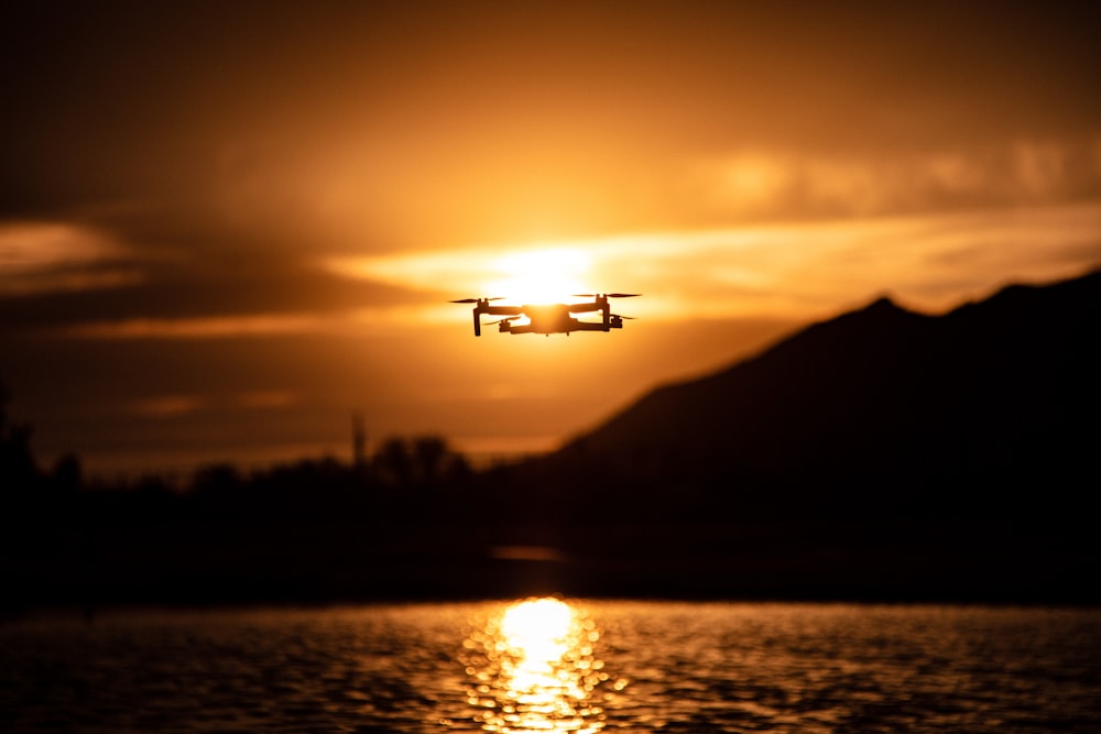 silhouette of airplane flying over the sea during sunset