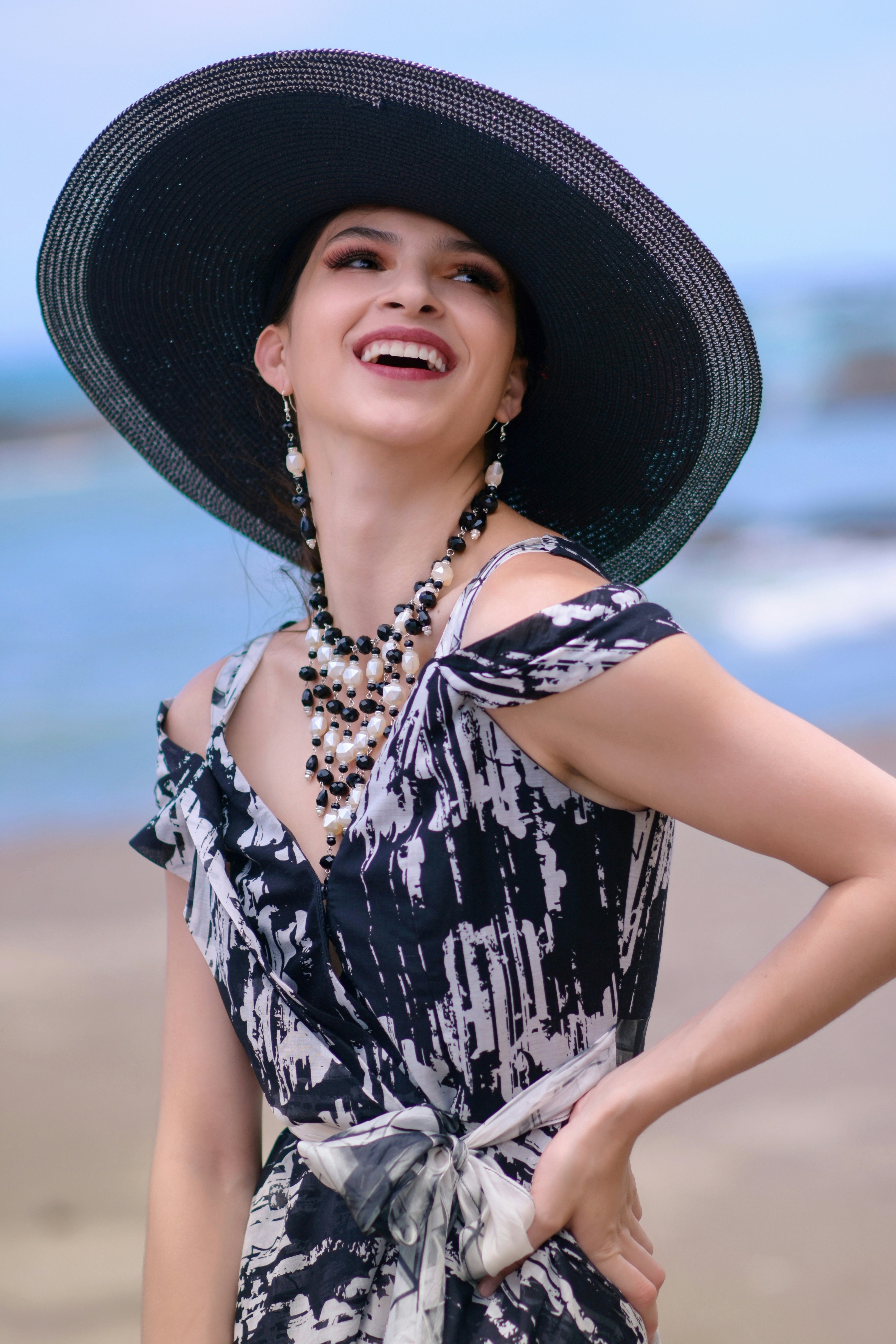 woman in black and white floral sleeveless dress wearing black sun hat