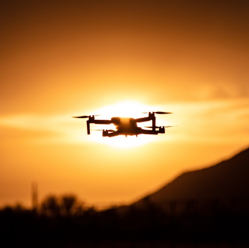 white drone flying during sunset