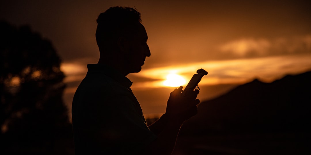 silhouette of man holding bottle during sunset