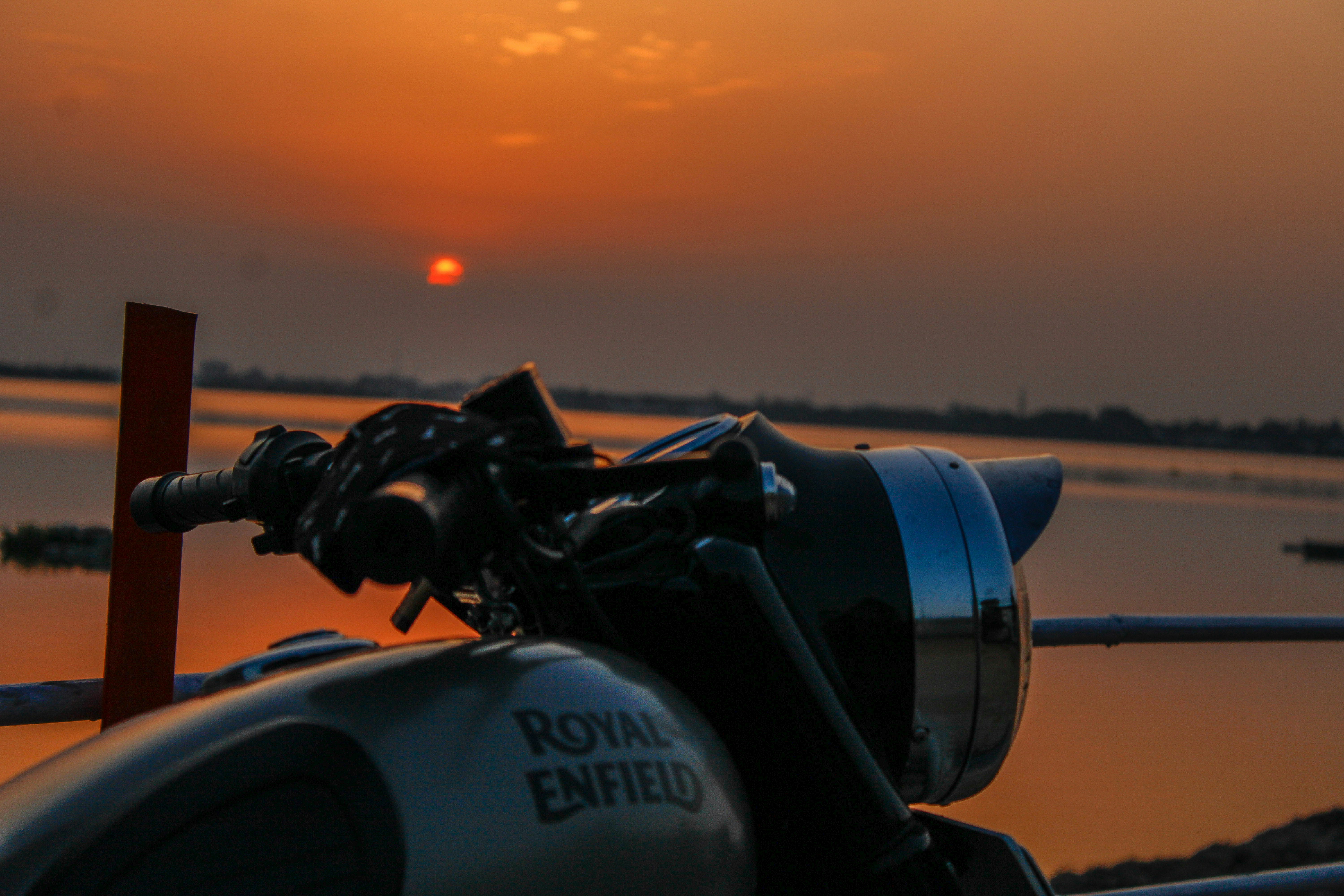 Royal Enfield motorcycle on coastal road with ocean view, golden hour light