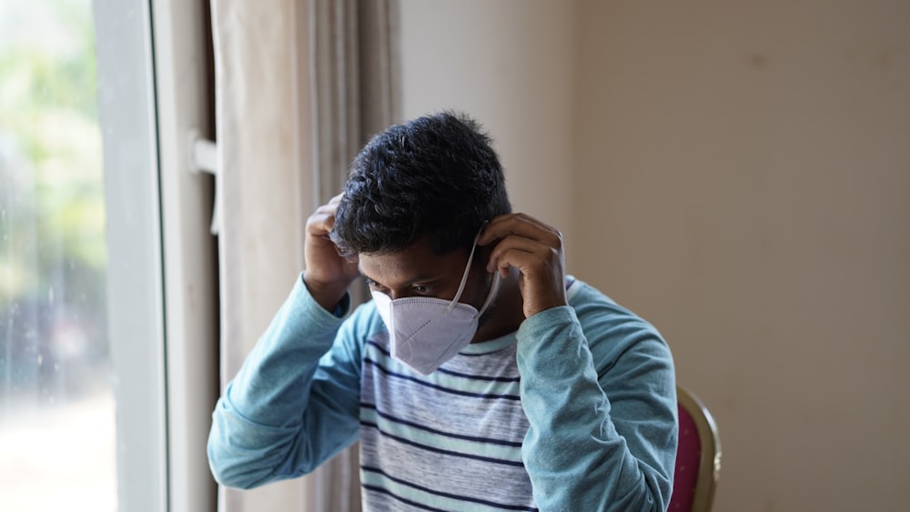 man in gray and white striped long sleeve shirt covering his face