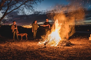 Joyful gathering around a sunset bonfire marking the end of the day