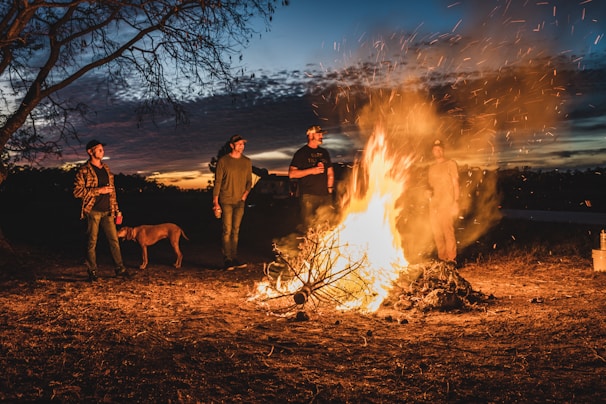 A sunset scene with friends sitting around a bonfire, sharing stories and smiles.
