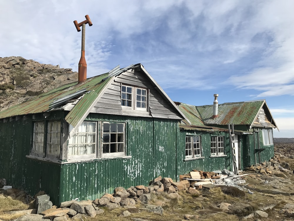 casa de madeira verde e branca sob o céu azul durante o dia