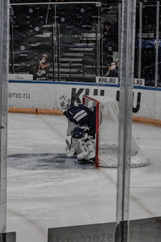 A focused goalie in full gear making a glove save during an intense practice session on an ice rink in CBS, Newfoundland.