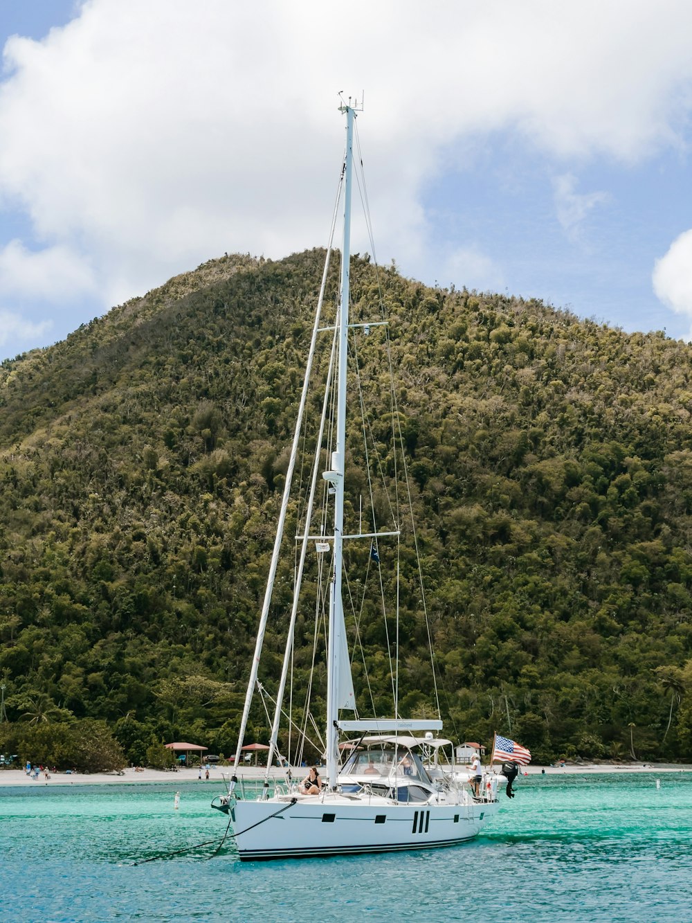 white boat on body of water near green mountain during daytime