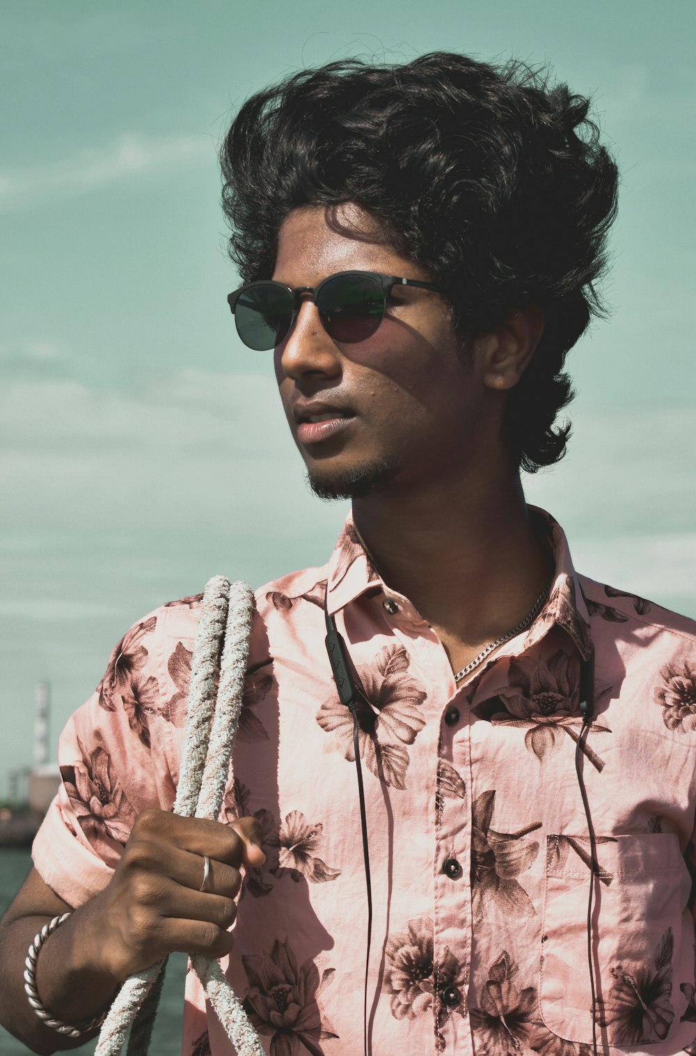 Hombre con camisa de botones florales rosa y blanco con gafas de sol negras