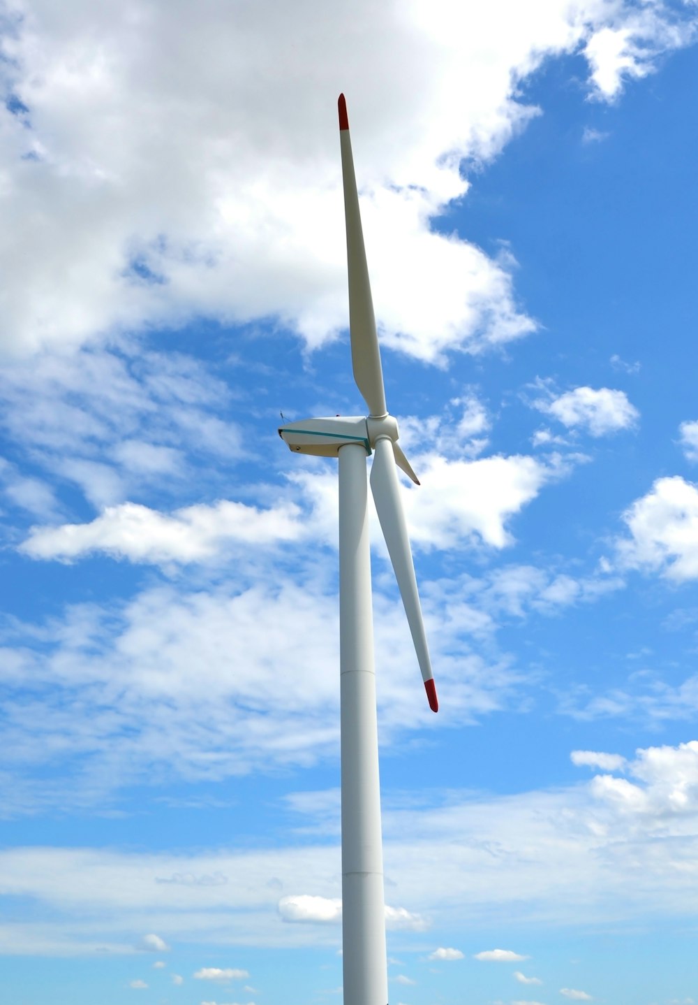 white wind turbine under blue sky and white clouds during daytime