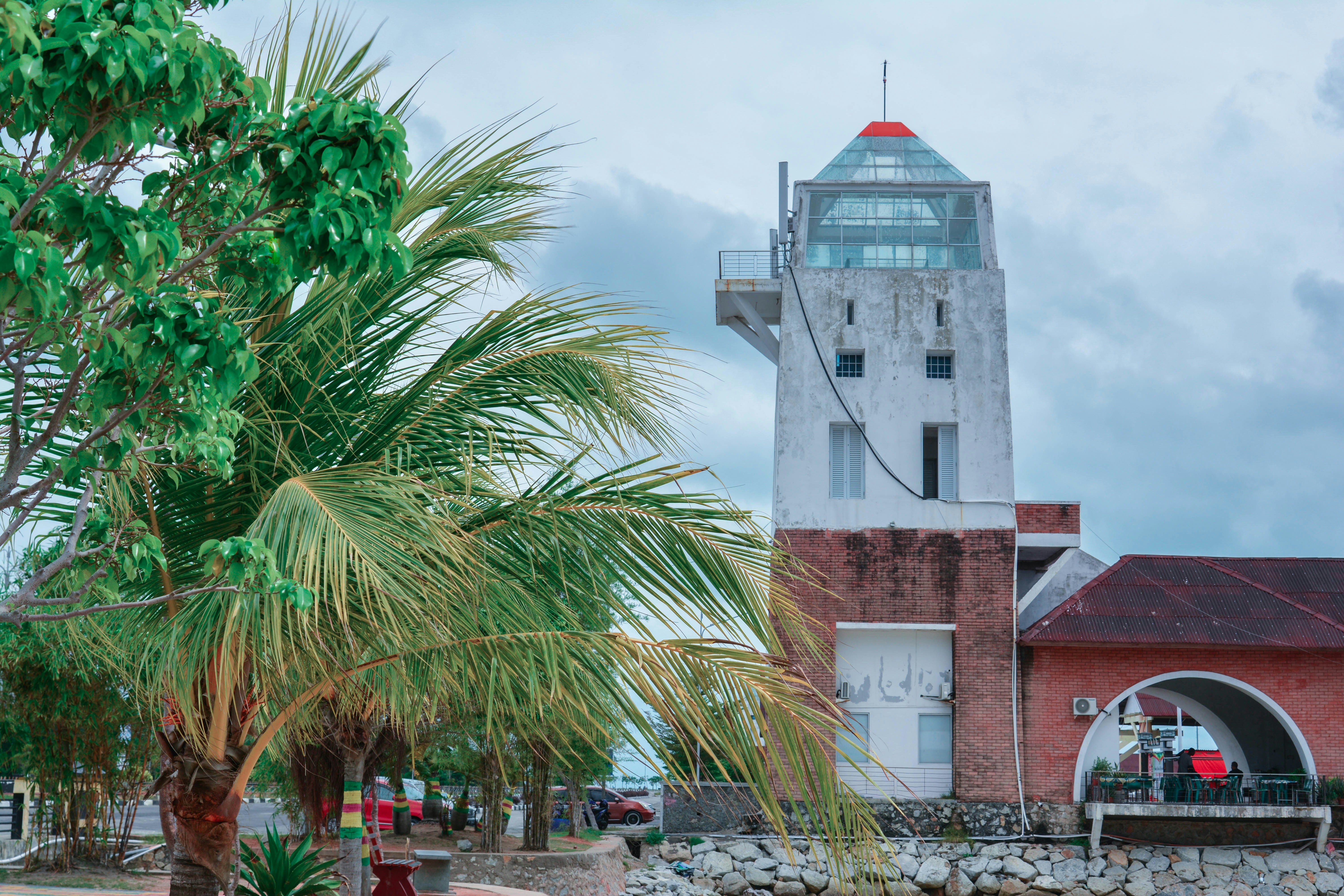 white and brown concrete building near palm tree under white clouds during daytime