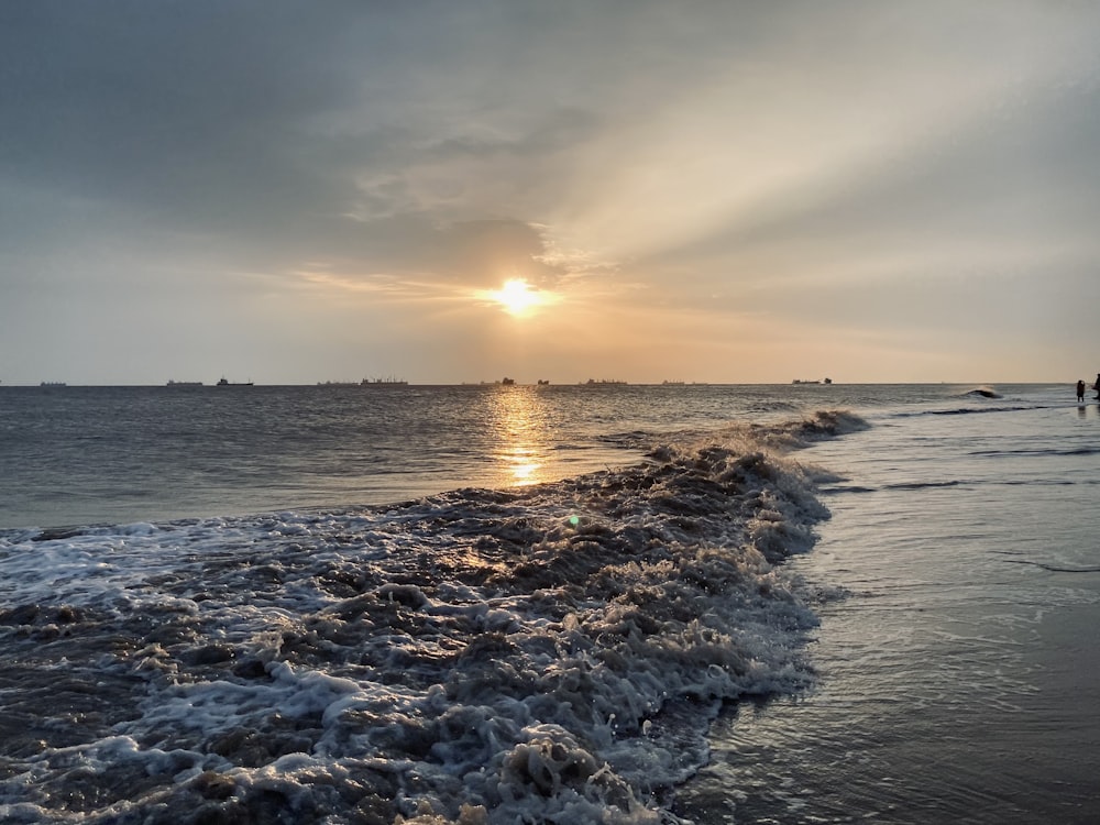 sea waves crashing on shore during sunset