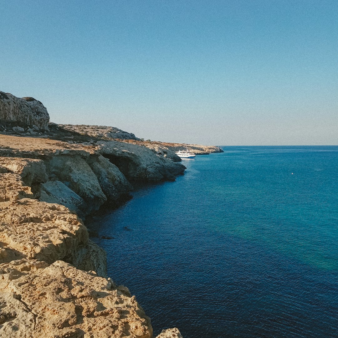 brown rocky mountain beside blue sea under blue sky during daytime