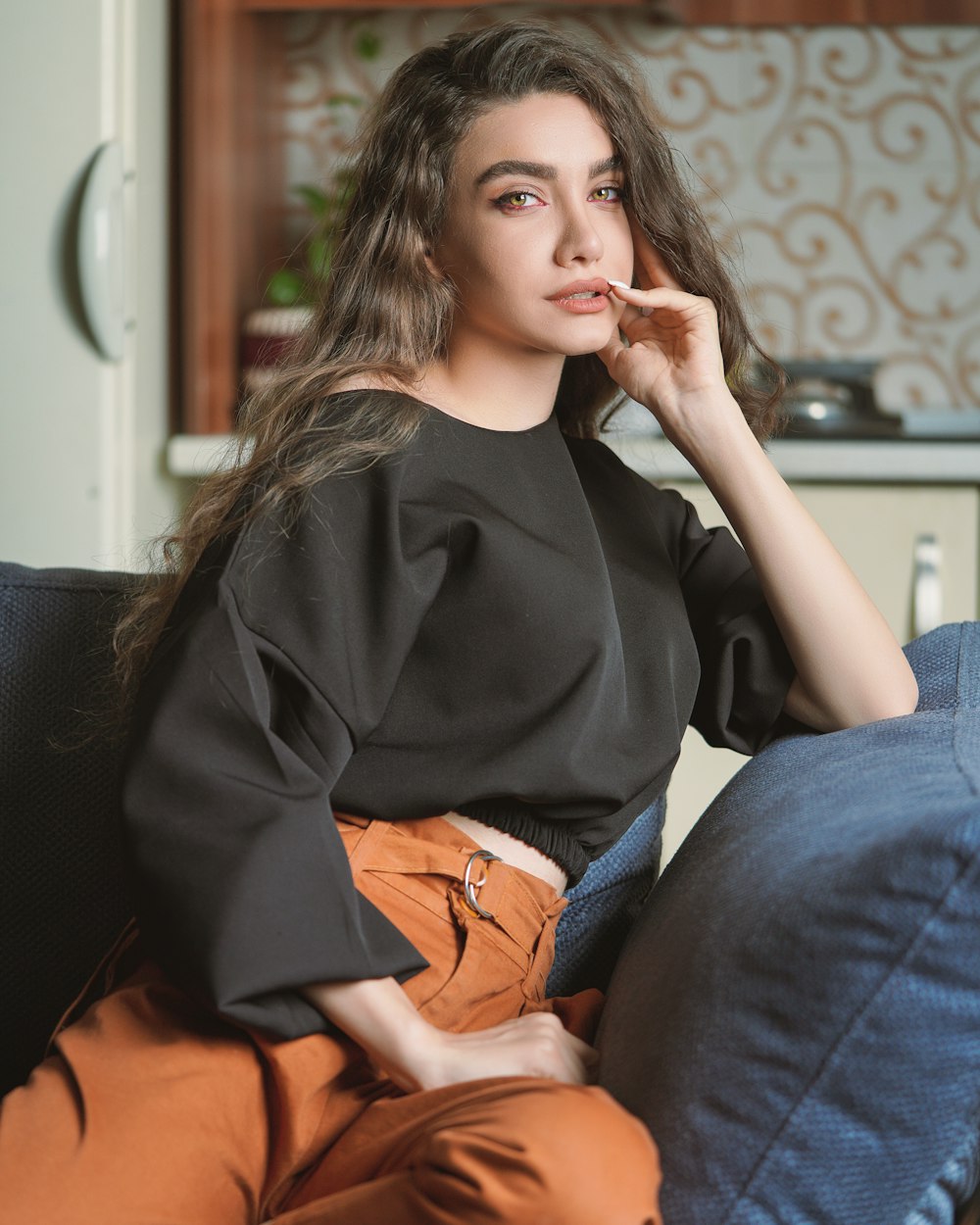 Mujer en camisa negra de manga larga y jeans de mezclilla azul sentada en un sofá negro