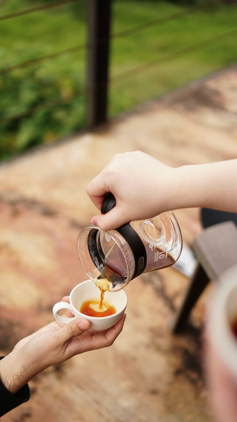 person holding clear plastic cup with brown liquid