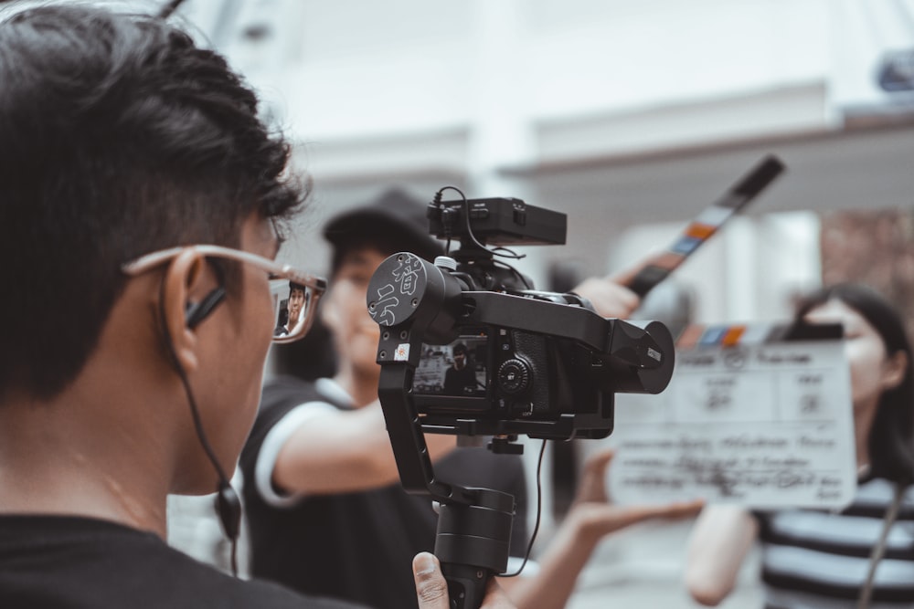 man in black framed eyeglasses holding black video camera