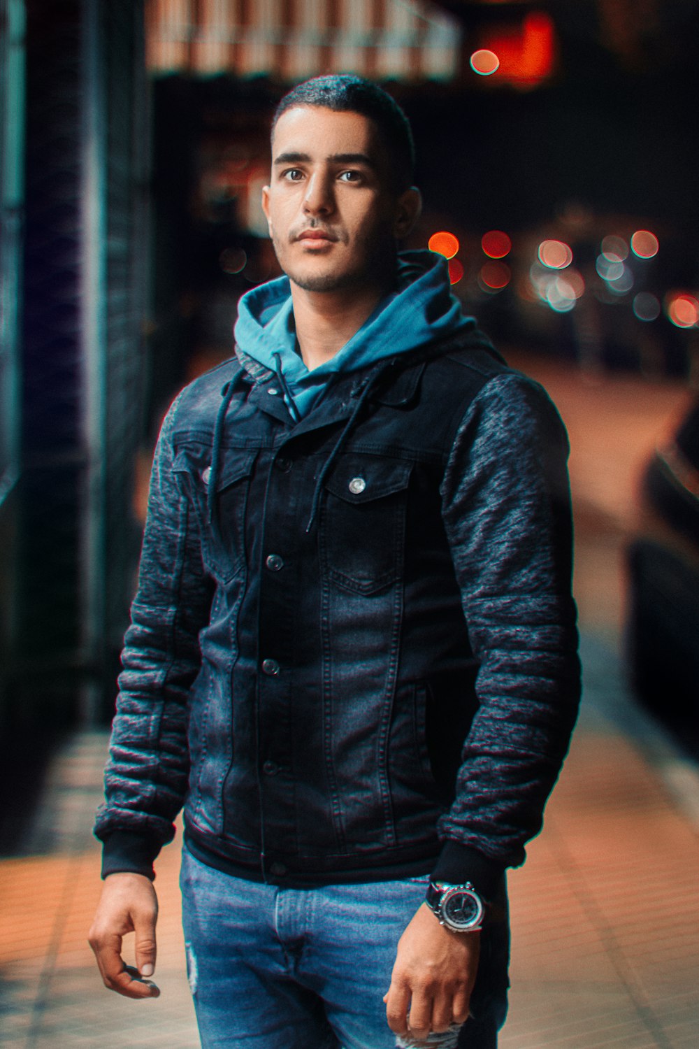 Mann in schwarzer Lederjacke steht nachts auf der Straße