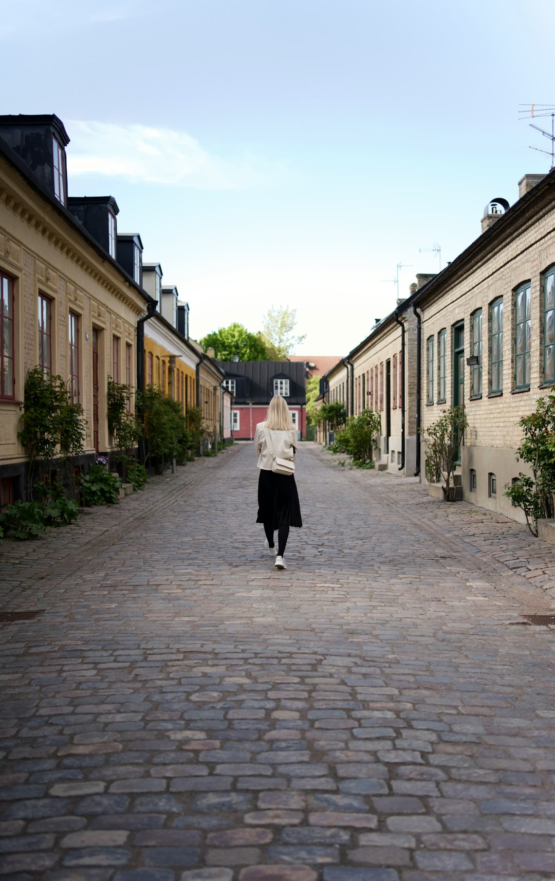 woman in white coat walking on sidewalk during daytime