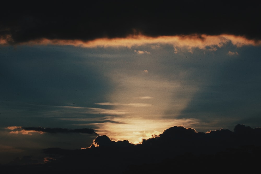 silhouette of mountain under cloudy sky during sunset