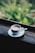 A steaming cup of coffee on a rustic wooden table surrounded by lush greenery.