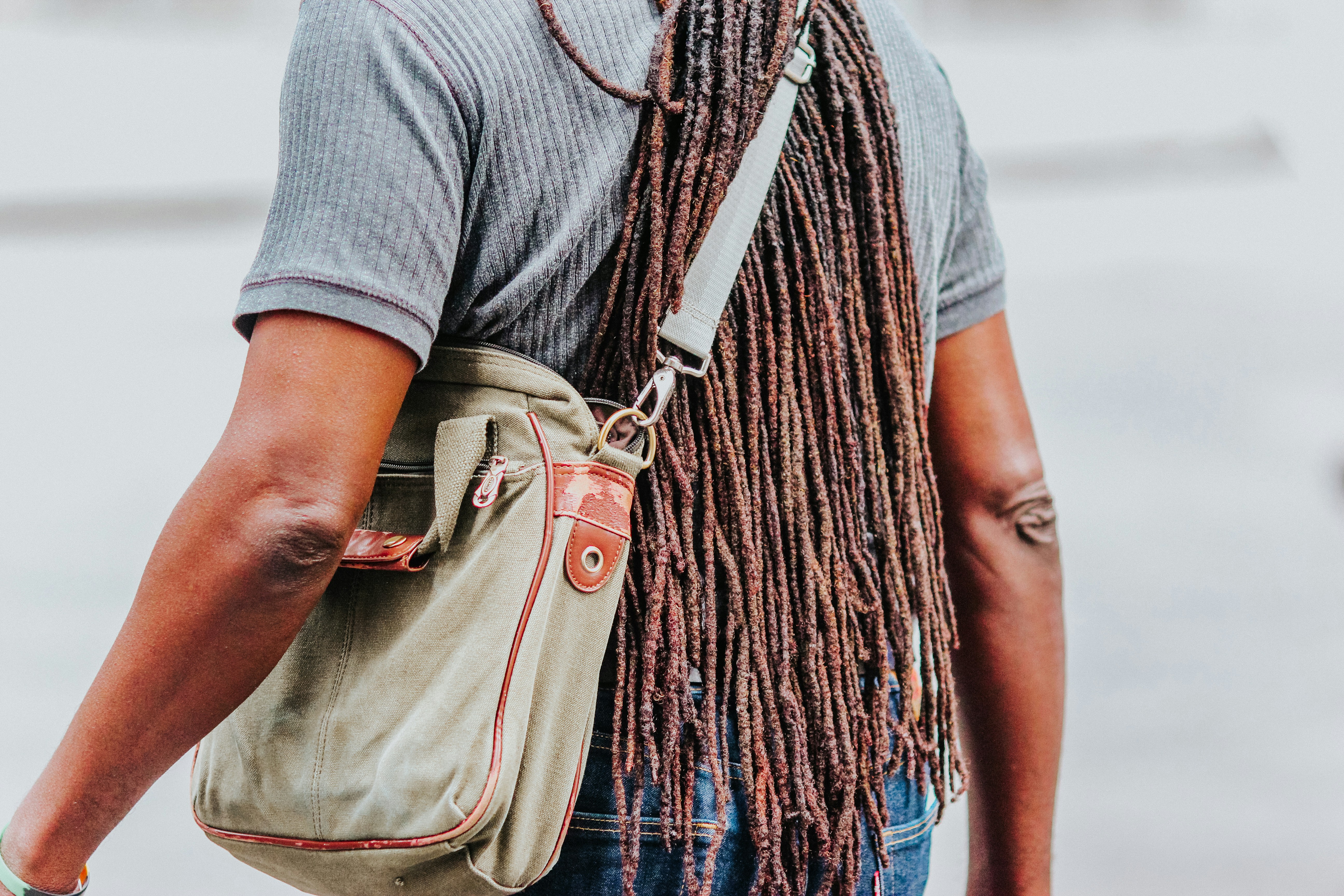 woman in gray shirt carrying brown leather sling bag