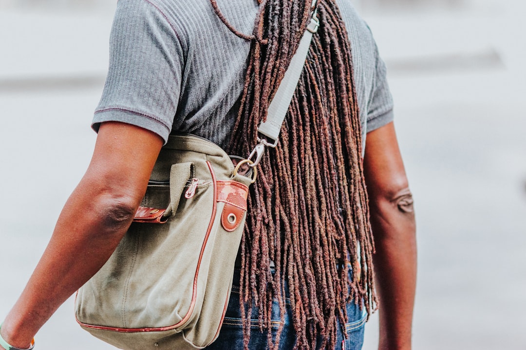 woman in gray shirt carrying brown leather sling bag