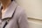 A close-up of a person wearing a textured beige or taupe jacket with a large collar. A gold and black chain strap is visible on the shoulder, suggesting a handbag or accessory.