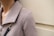 A close-up of a person wearing a textured beige or taupe jacket with a large collar. A gold and black chain strap is visible on the shoulder, suggesting a handbag or accessory.