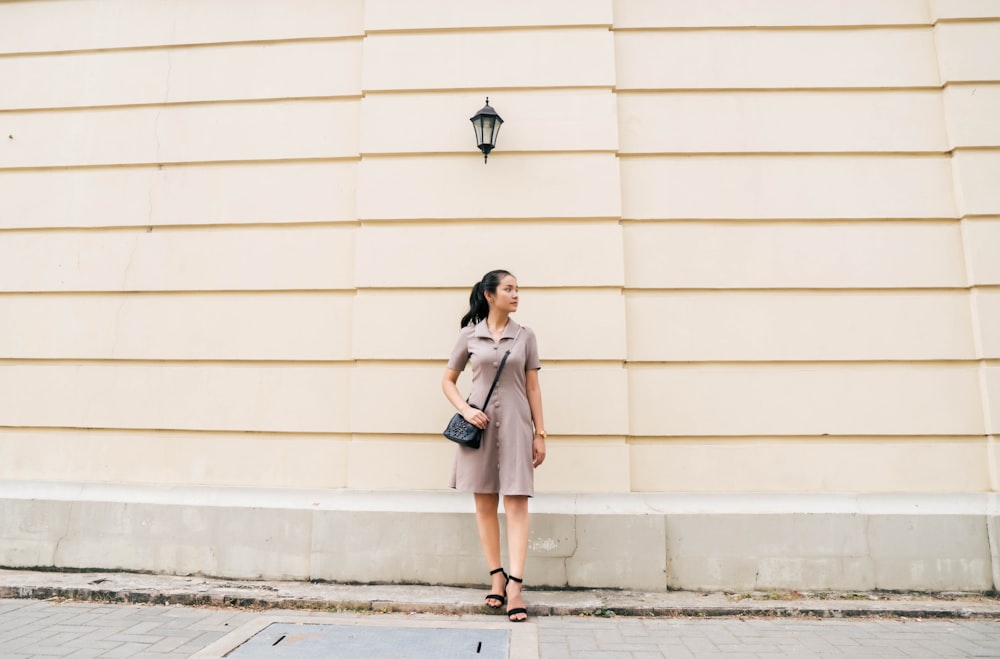 woman in brown blazer and brown skirt standing on sidewalk during daytime