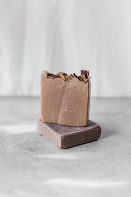 Close-up of handmade honey and aloe vera soap bars arranged on a rustic wooden surface with natural plants around.