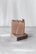 Two handmade soap bars are stacked on a textured gray surface. The top soap bar has a rustic, natural appearance with dried flowers embedded on the surface. The background is softly blurred in a light, neutral tone, giving a minimalist aesthetic.