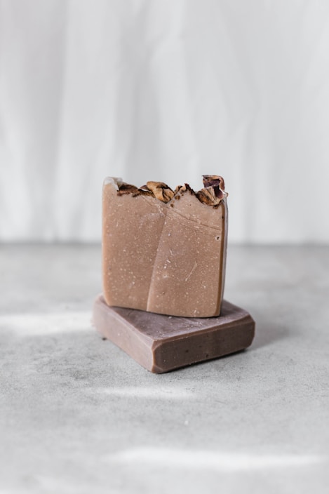 Close-up of handmade honey and aloe vera soap bars arranged on a rustic wooden surface with natural plants around.