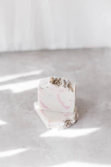 Artisan natural soaps stacked with fresh herbs and flowers on a rustic wooden surface