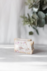 Close-up of a grape-shaped soap cluster hanging elegantly from a kitchen faucet, sunlight highlighting its gentle colors.