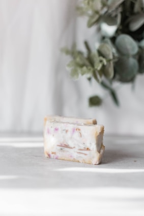 A soap bar with a defined edge resting on a green leaf background