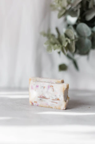 A rustic soap bar resting on a wooden surface with fresh herbs scattered around in an urban loft setting.