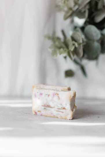 Close-up of a delicate herbal soap bar with natural leaves around it, highlighting its gentle texture.