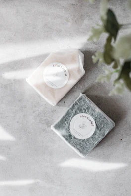 Elegant soap bars decorated with swirls of clay and essential oils, resting on a sage green background.