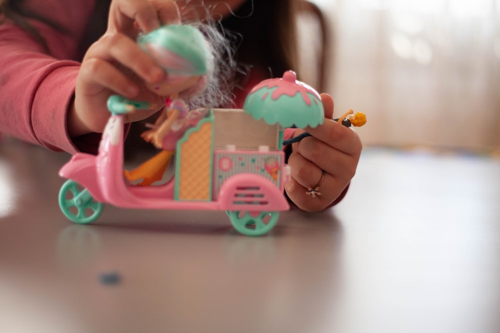 girl holding pink and white plastic toy