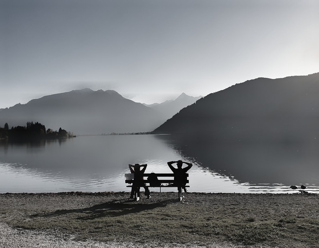 man sitting on bench near lake during daytime