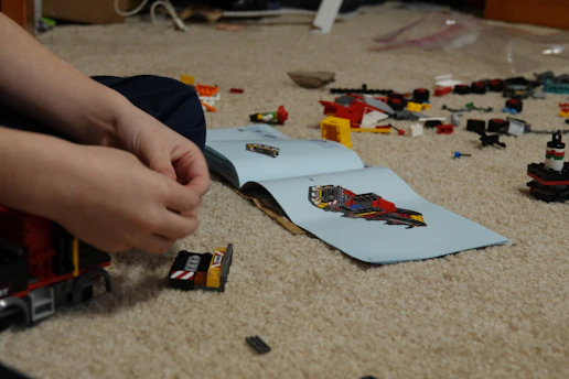 A close-up of hands assembling a detailed LEGO® model with bricks scattered around.