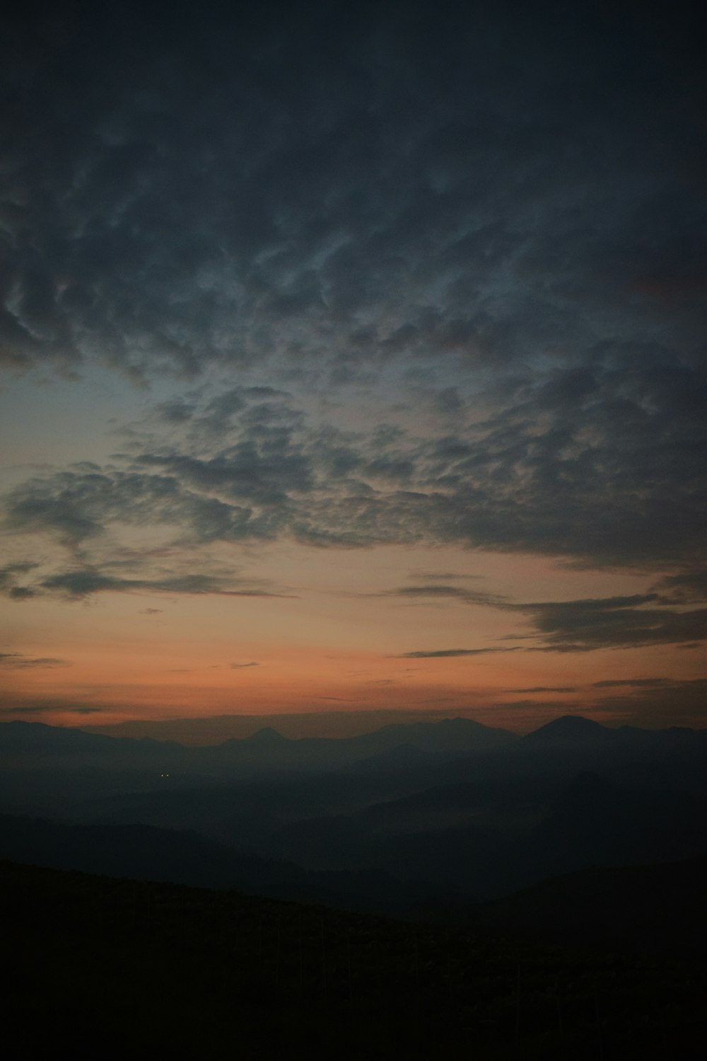 夕暮れ時の曇り空の下の山々のシルエット