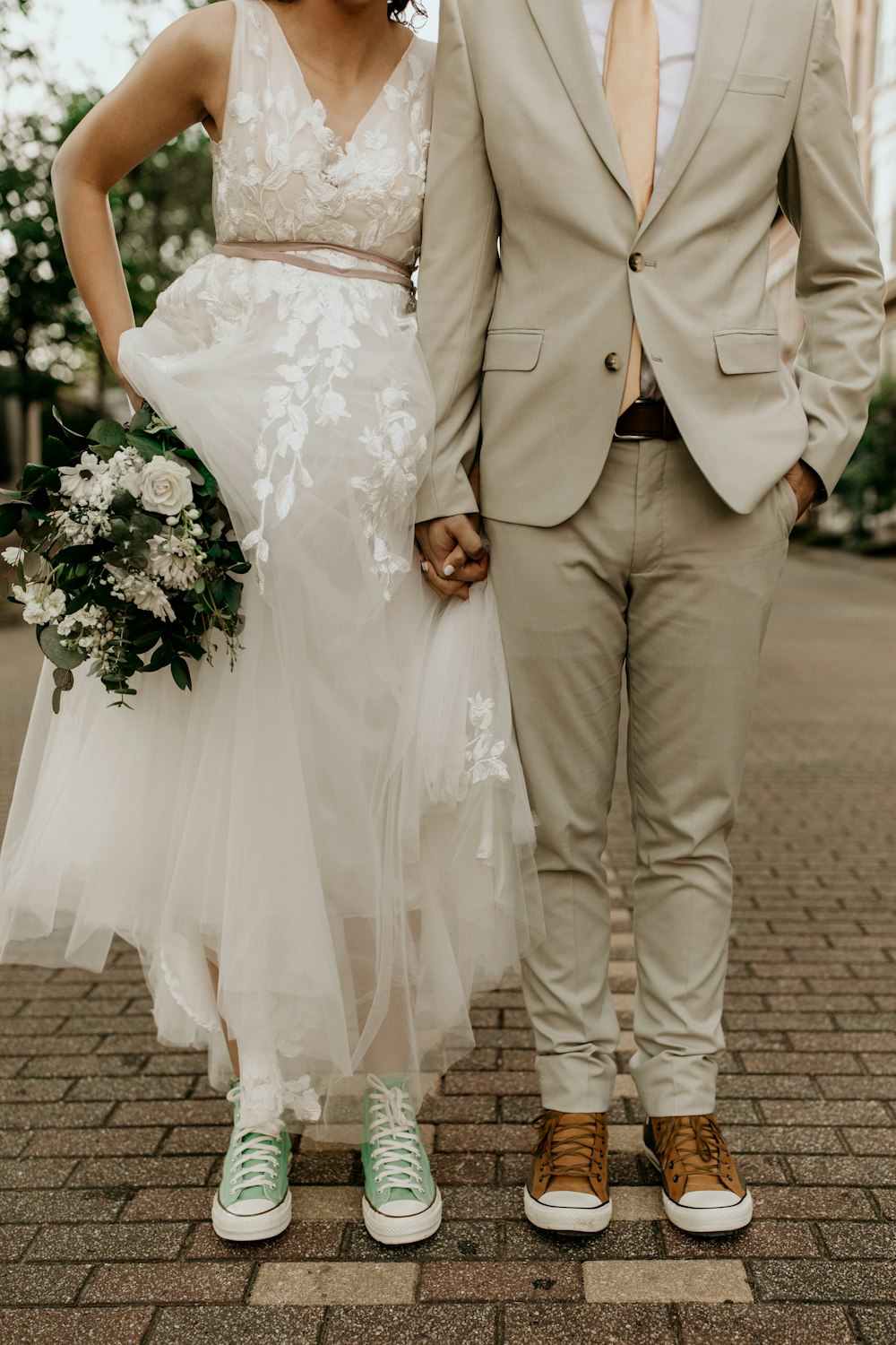 hombre con chaqueta de traje gris y mujer con vestido de novia blanco con ramo de flores blancas