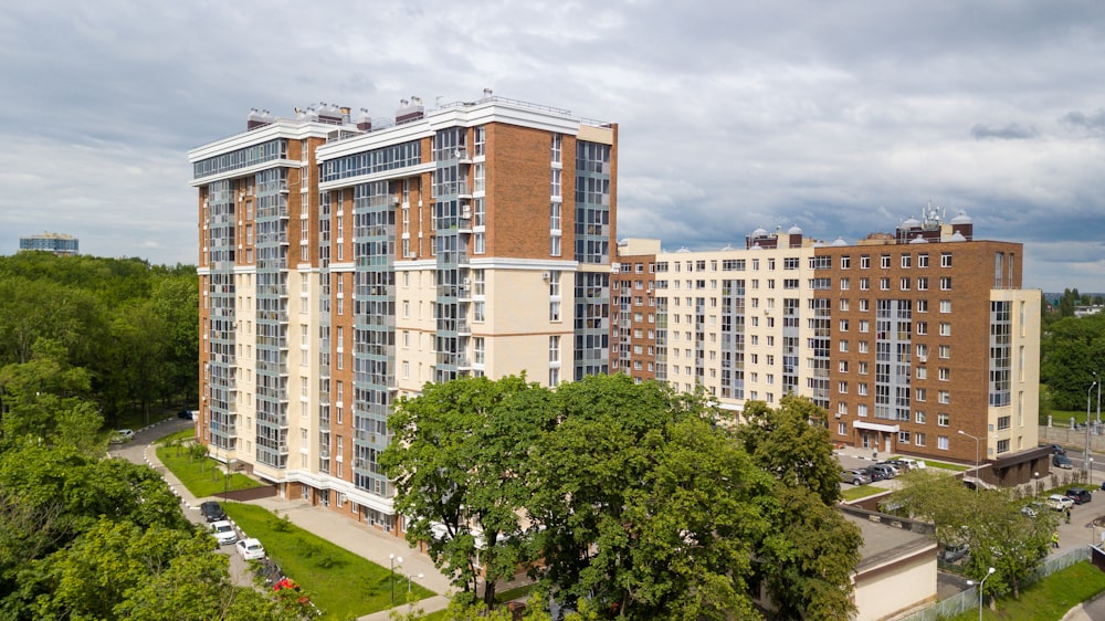 white and brown concrete building near green trees under white clouds during daytime